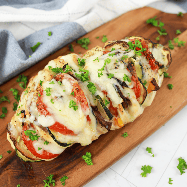 Air Fryer Primavera Stuffed Chicken with colorful vegetables and melted cheese, served on a plate.