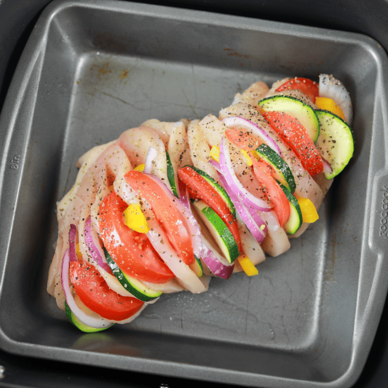 Placing stuffed chicken in the air fryer basket – Stuffed chicken breasts arranged in the air fryer basket, ready for cooking.