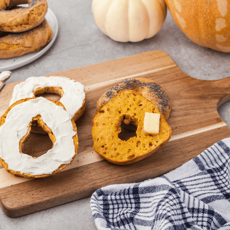 Air Fryer Pumpkin Bagels on a cutting board with cream cheese and butter