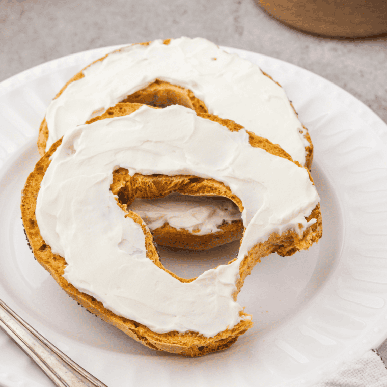 Pumpkin Bagels on a white plate, with cream cheese on top.