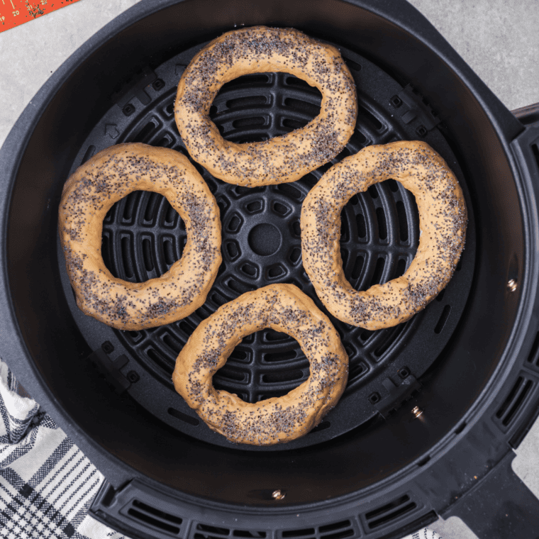 Placing the shaped pumpkin bagels into the air fryer basket, ready for cooking
