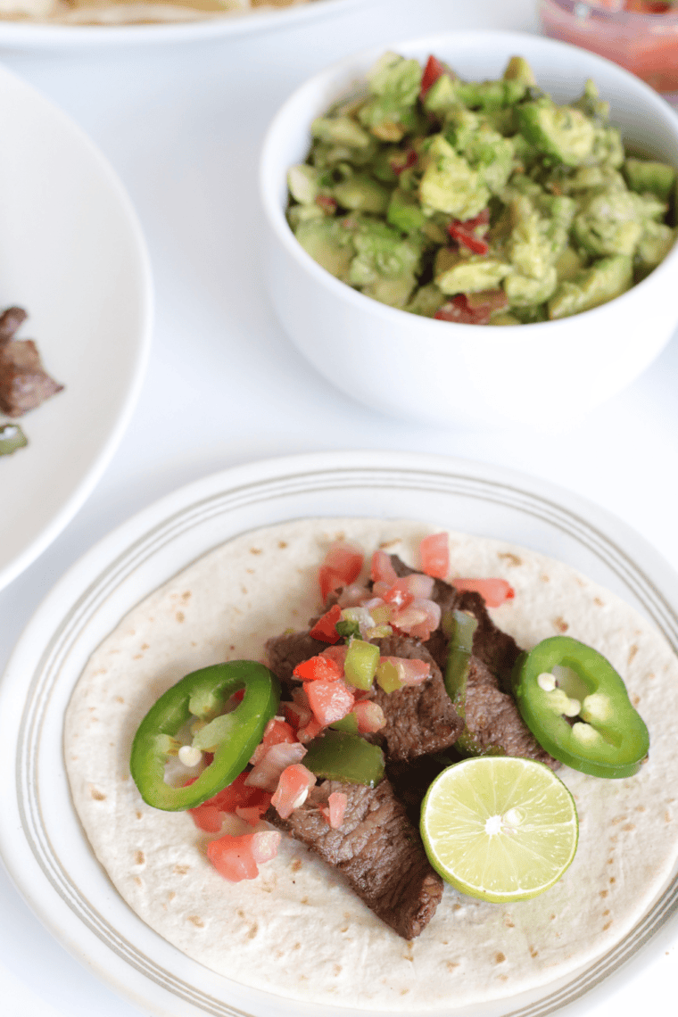 Air fryer steak fajitas assembled on a tortilla with toppings, ready to serve