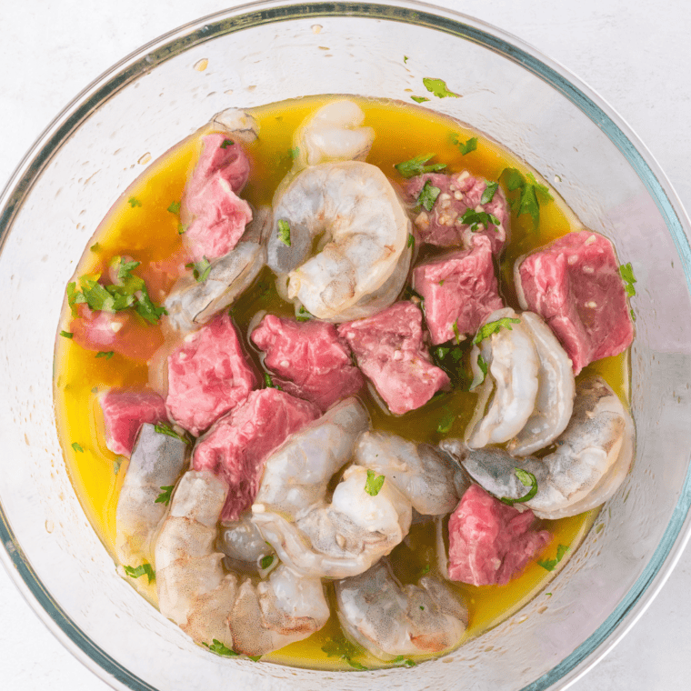 Surf and turf kebabs with steak cubes and shrimp threaded onto skewers, evenly spaced for optimal cooking.