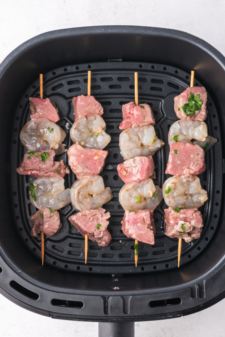 Surf and turf kebabs arranged in an air fryer basket, ready to cook at 400°F for 8-10 minutes, turned halfway for even cooking.
