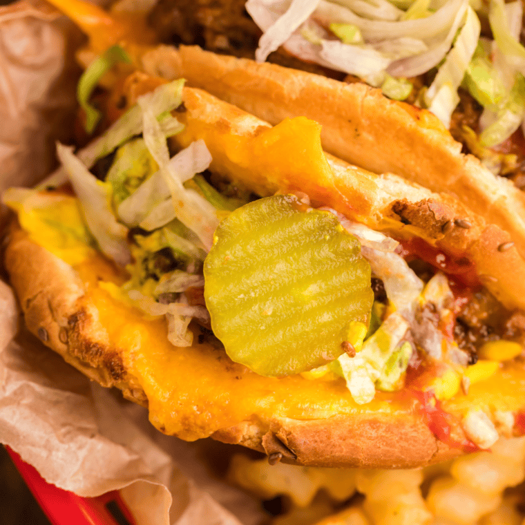 Close-up of crispy Air Fryer Taco Burgers with melted cheese, ground beef, lettuce, and pickles on a sesame seed bun.