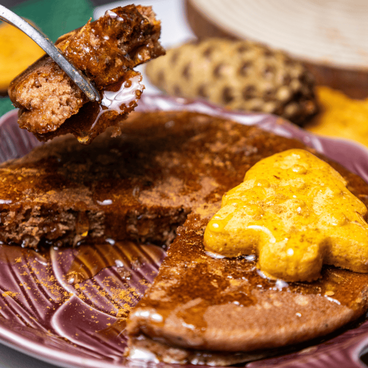 A single brown sugar pancake on a brown plate with a fork taking a bite