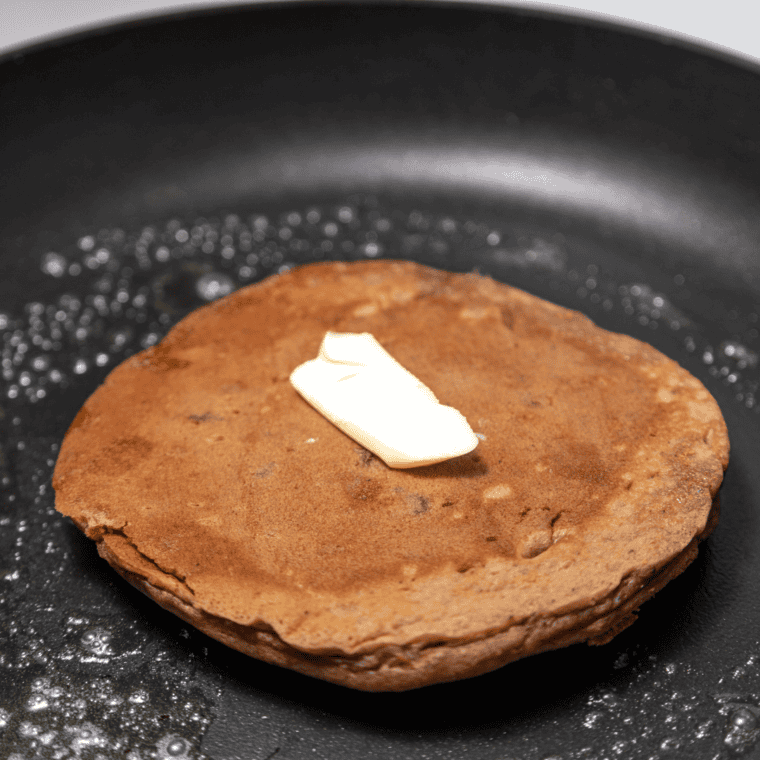 Pancakes cooking on hot griddle until bubbles form and edges set before flipping