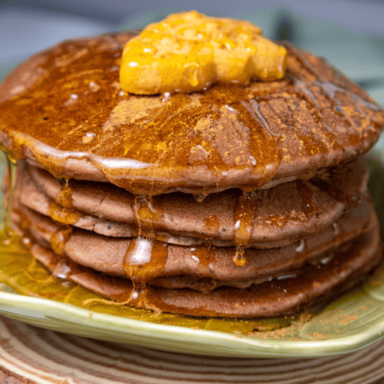 Stack of warm pancakes kept in oven and served with syrup and toppings