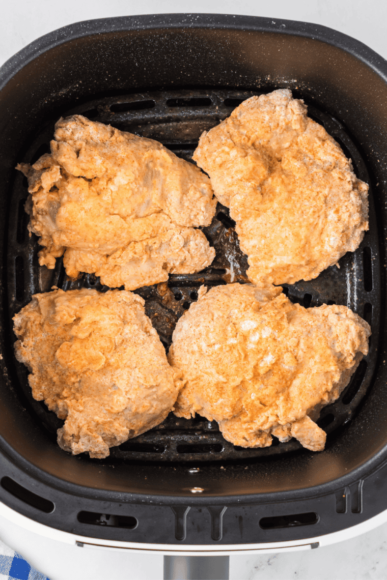 Placing coated chicken pieces in the air fryer basket, ready for cooking.