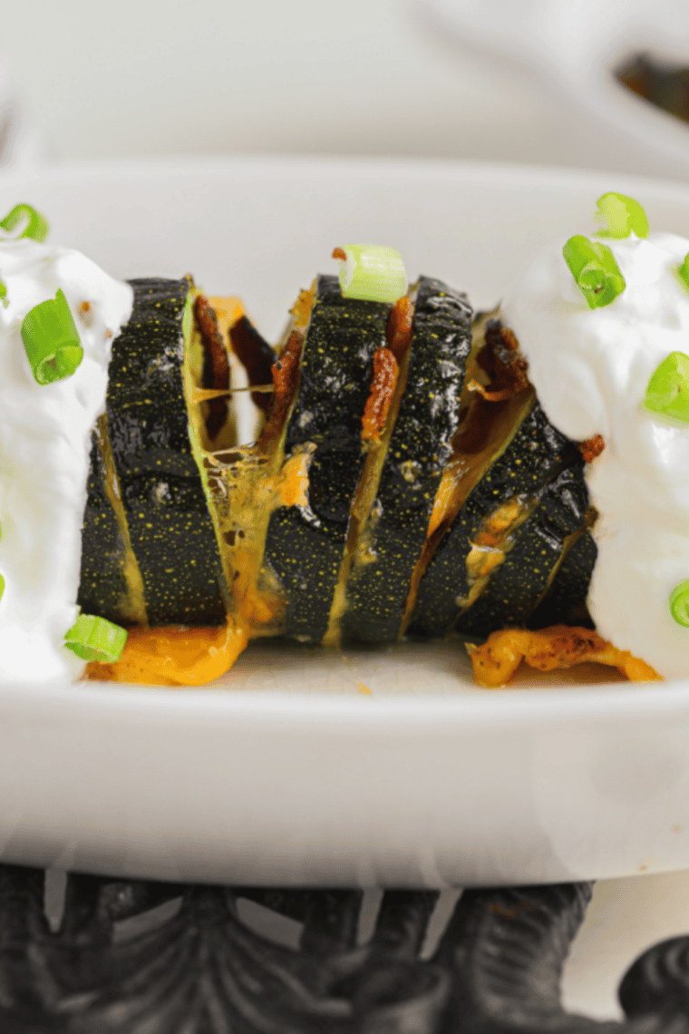 Golden-brown Hasselback zucchini in an air fryer, topped with herbs and melted cheese.