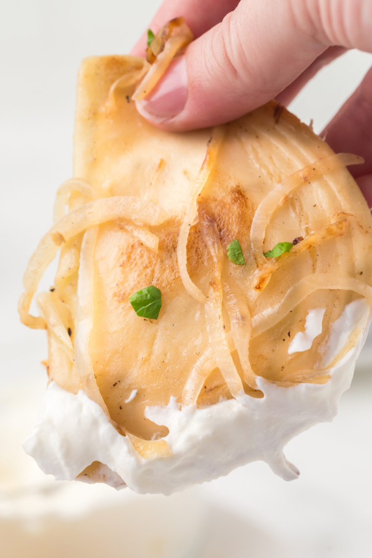 Crispy pierogies on a Blackstone griddle topped with sweet caramelized onions