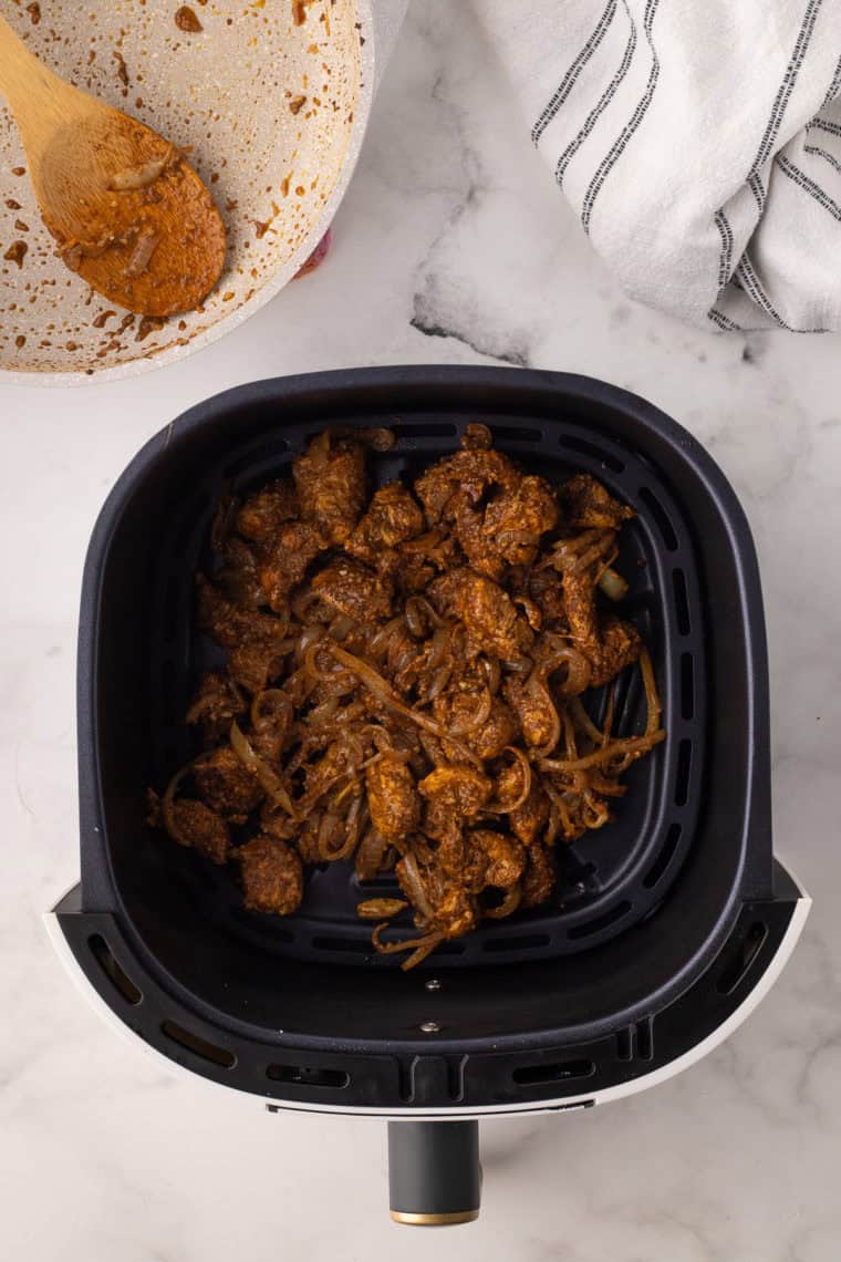 Baking dish covered with foil placed in the air fryer, cooking biryani at 320°F for final layering.
