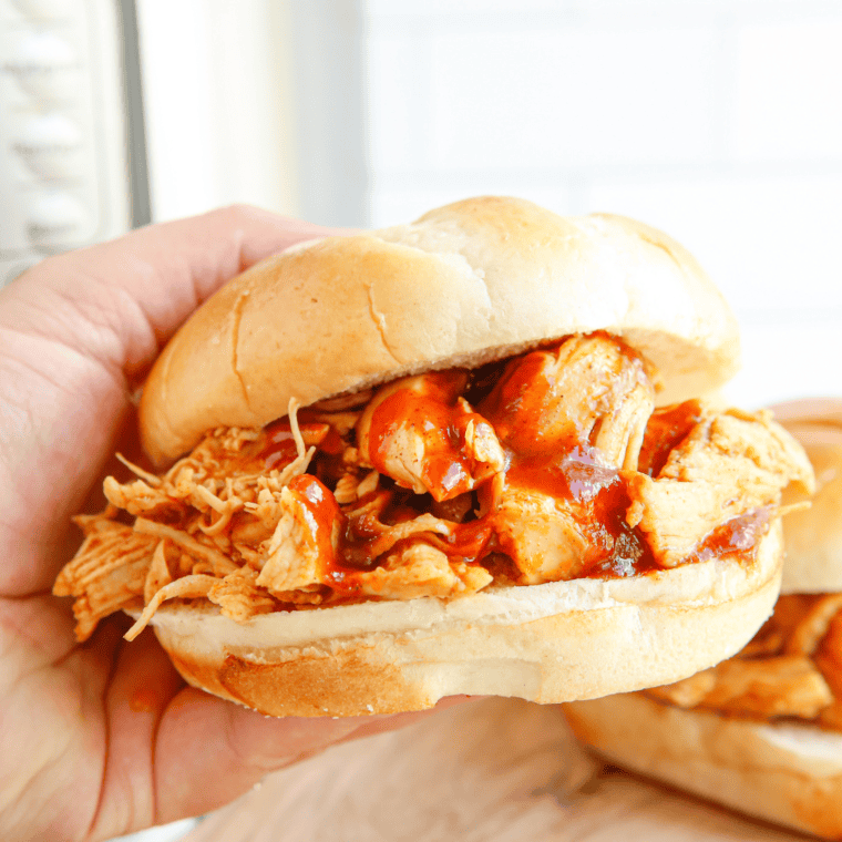 Tender shredded BBQ chicken in an Instant Pot with two forks resting on the rim.
