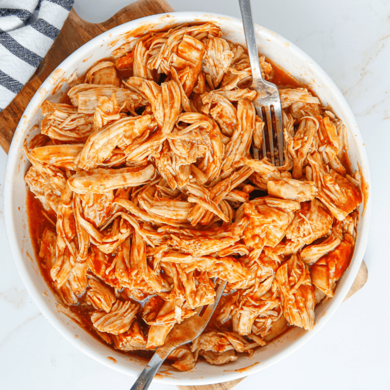 Shredding tender BBQ chicken with two forks directly in the Instant Pot.