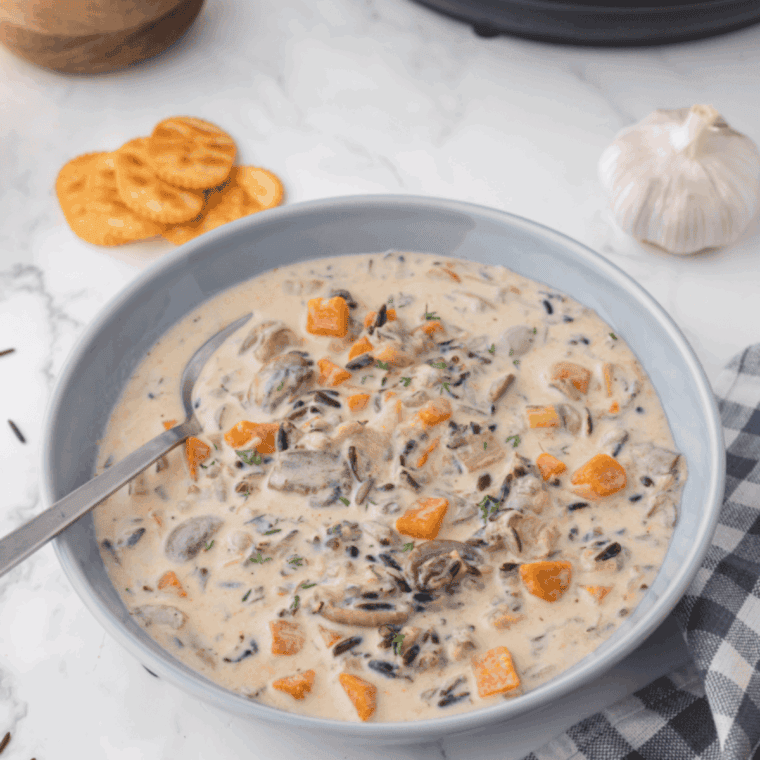 Bowl of creamy Instant Pot Panera Bread copycat chicken wild rice soup with tender chicken, wild rice and vegetables topped with fresh parsley.