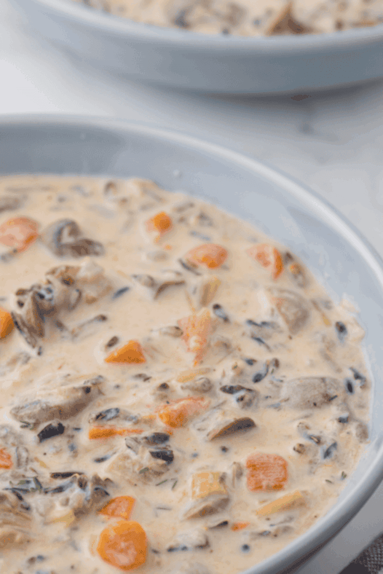 Bowl of Instant Pot Panera Bread copycat chicken wild rice soup, creamy with tender chicken, wild rice, and vegetables, garnished with fresh parsley.
