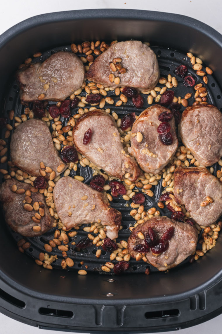 Checking the internal temperature of air-fried pork medallions with a meat thermometer."
