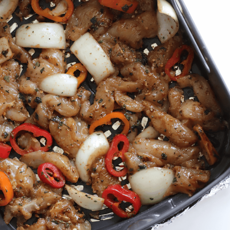 Seasoned chicken fajita strips arranged in a single layer in the Ninja Foodi air crisp basket