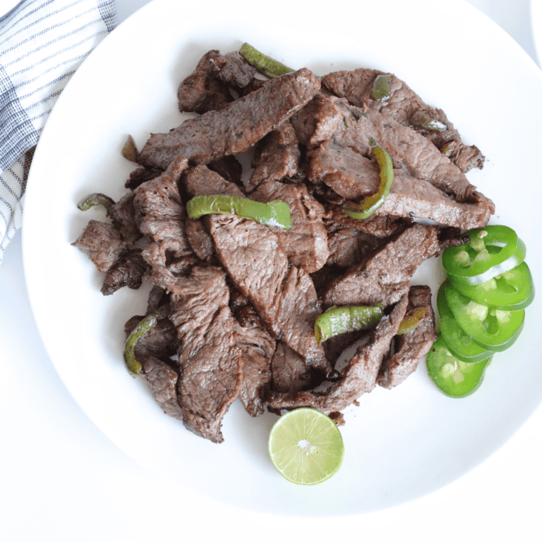 Grilled steak fajitas with bell peppers and onions served on a plate.