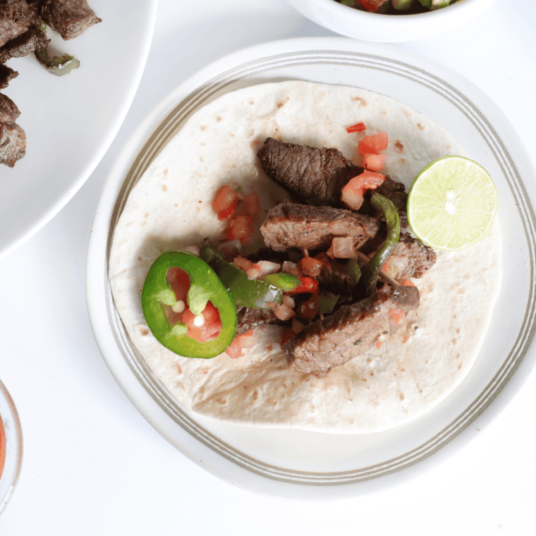 Juicy grilled steak fajitas with onions and bell peppers on a plate.