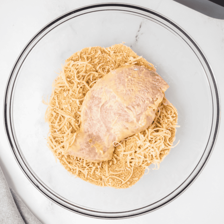 Adding the breading onto the chicken, making sure it adheres well.