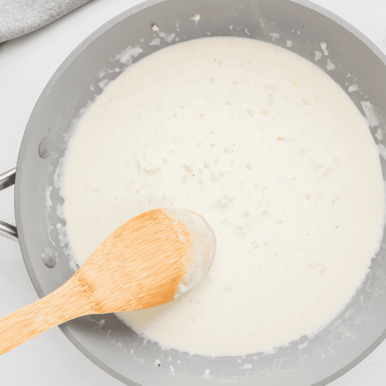 Preparing creamy garlic sauce for Olive Garden Chicken Scampi in a saucepan.