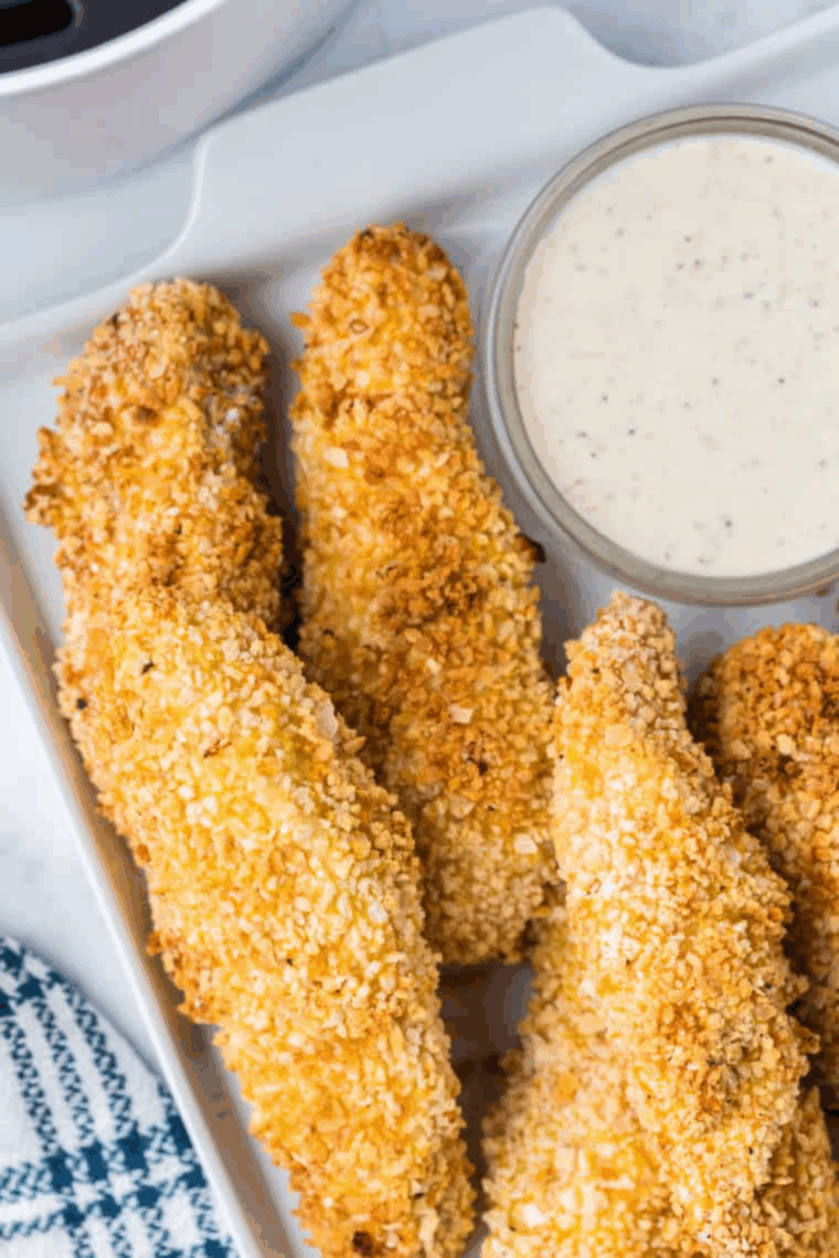 Golden, crispy homemade Whataburger-style chicken strips served on a plate with dipping sauce.