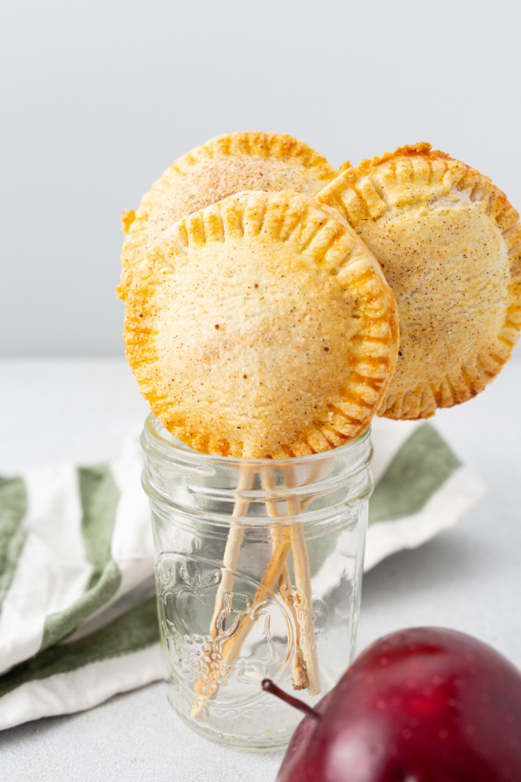 Air fryer apple pie pops with golden flaky pastry and cinnamon-spiced apple filling on sticks