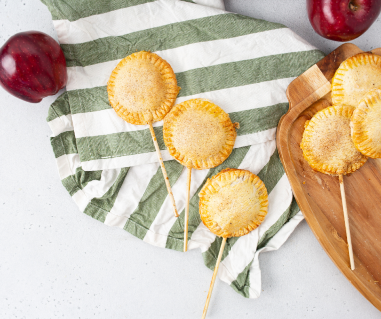 Air fryer apple pie pops with golden flaky pastry and cinnamon-spiced apple filling on sticks