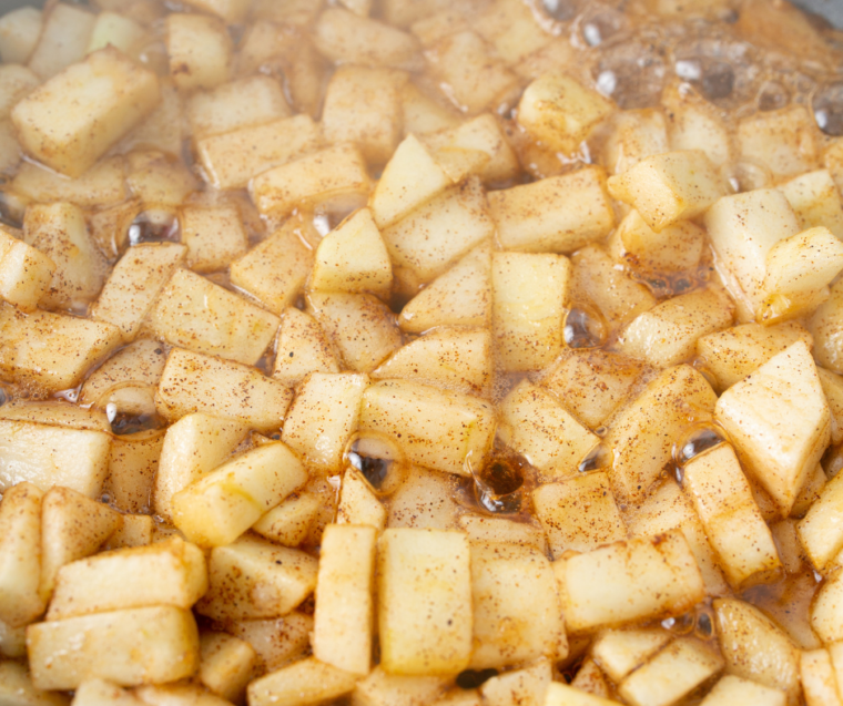 Skillet of apples cooking with sugar, spices, lemon juice, and cornstarch mixture thickening to make apple pie filling