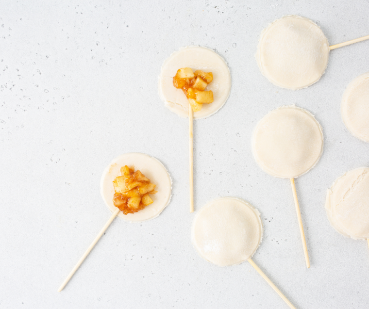 Pie crust rolled into circles on floured surface with round and leaf cutouts being made