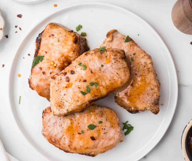 Golden air fryer apricot pork chops glazed with apricot preserves on a white plate