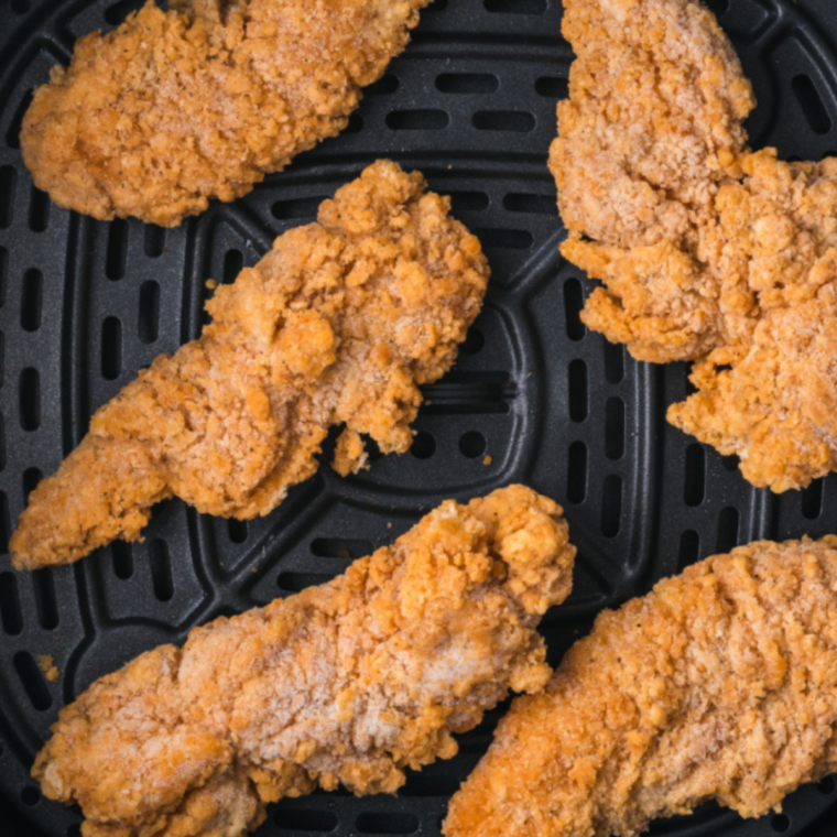 Frozen breaded chicken tenderloins in a single layer in an air fryer basket