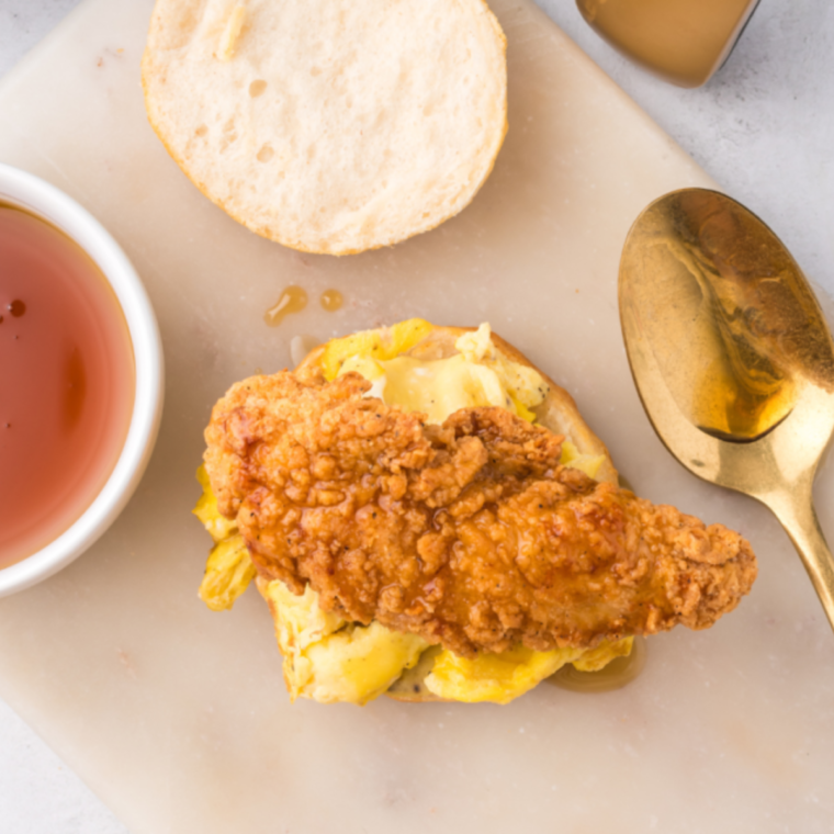 Assembling a chicken biscuit sandwich by layering crispy chicken on a split biscuit