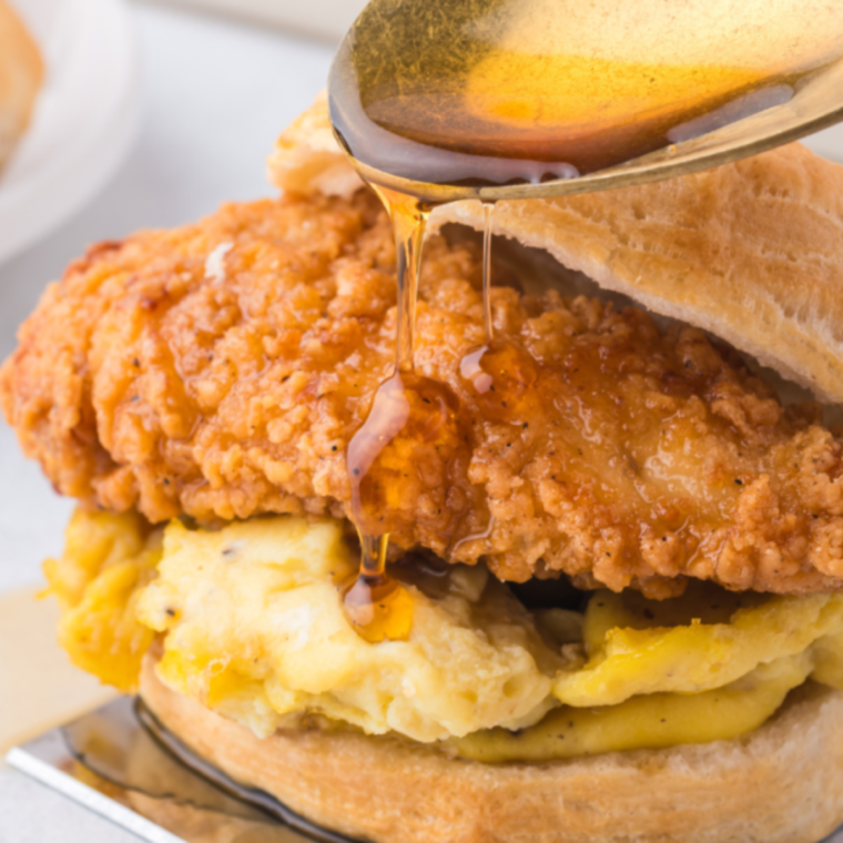 Air Fryer Chicken Biscuit Sandwiches drizzled with maple syrup on a white plate