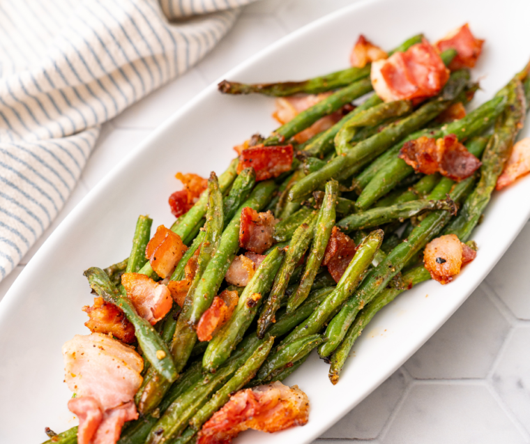 Air-fried green beans mixed with crispy bacon pieces, served hot on a plate.