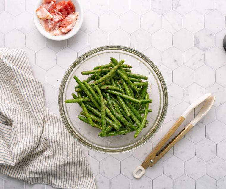 Fresh green beans being trimmed and rinsed under cold water, then dried with a clean towel.