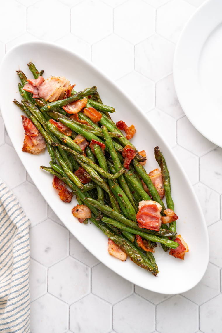 Crispy air-fried green beans mixed with crispy bacon bits, served on a plate.