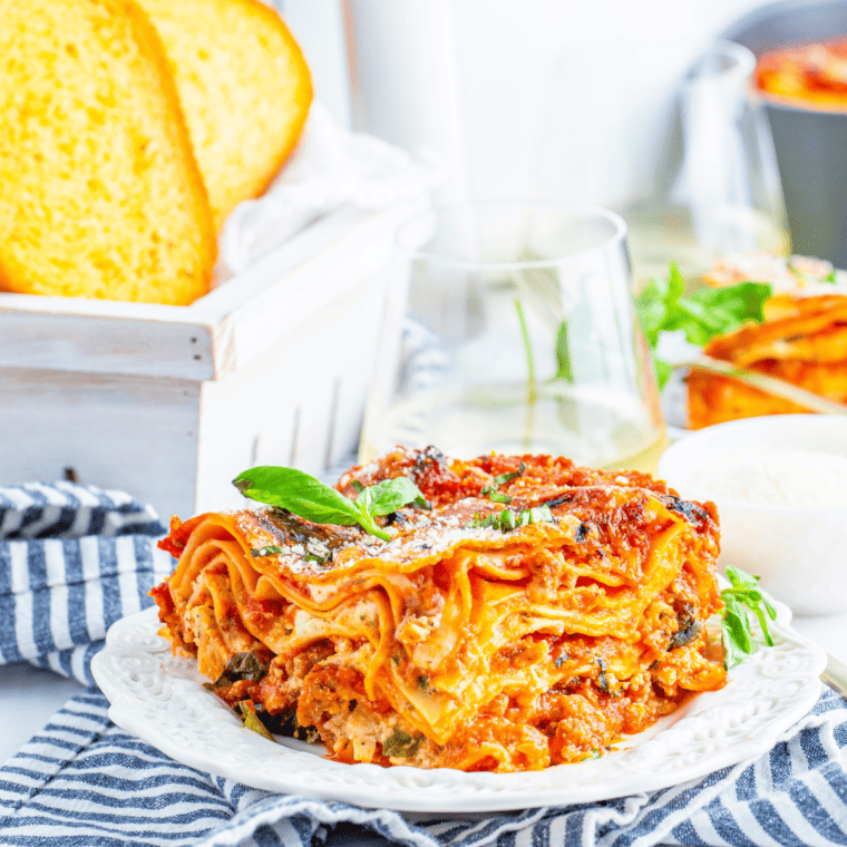 Air fryer lasagna with Italian sausage, ricotta, and bubbly golden mozzarella in an 8x8 dish, garnished with fresh basil