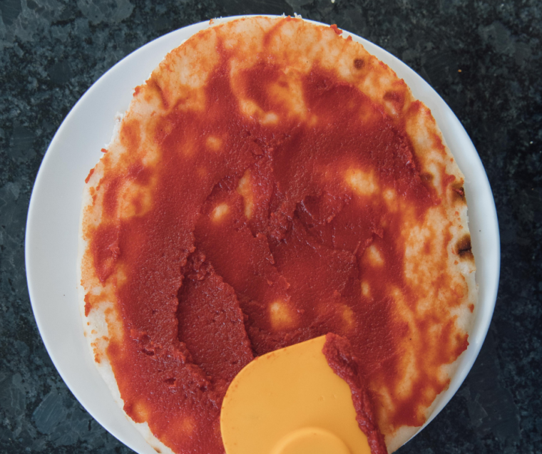 Spread the pizza sauce over the flatbread.