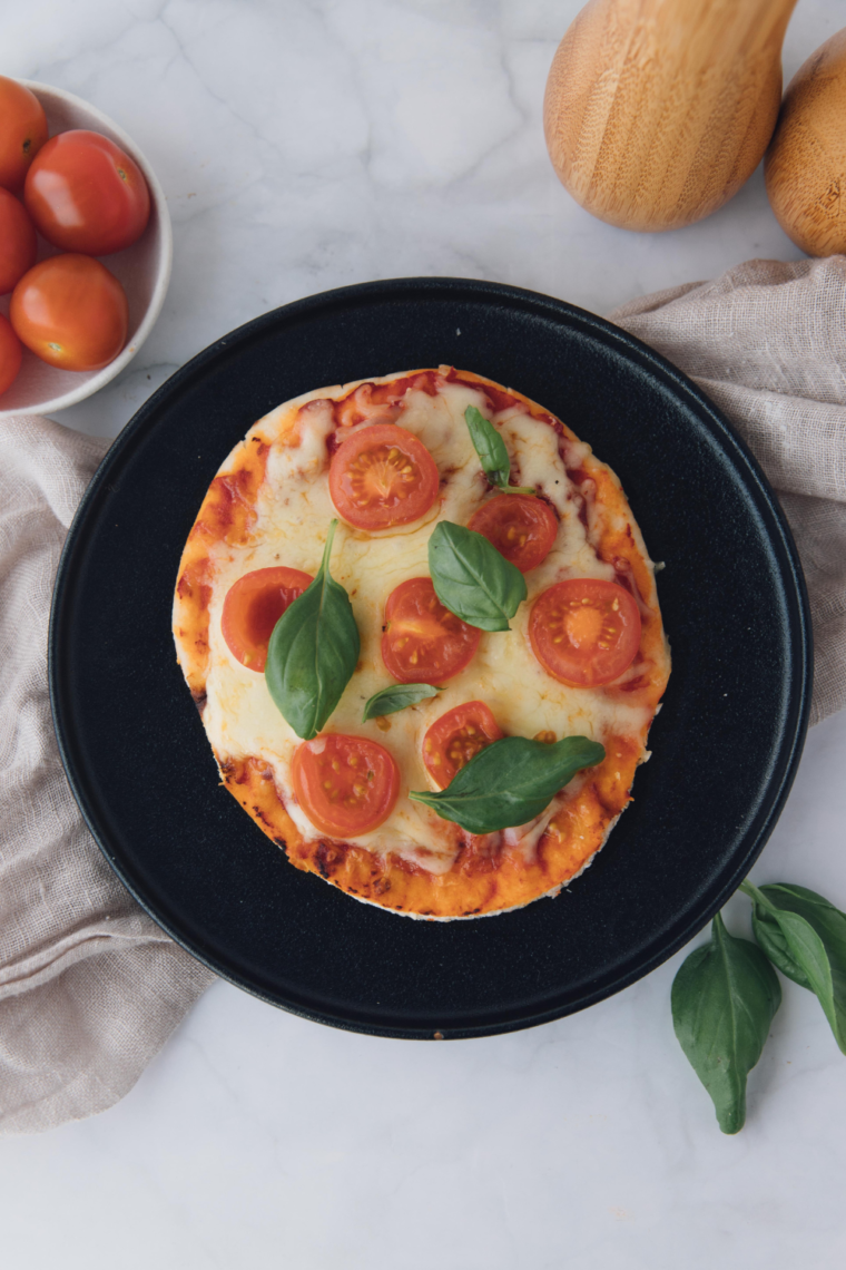 Panera-style Margherita Flatbread Pizza with melted mozzarella, sliced tomatoes, and basil on a cutting board
