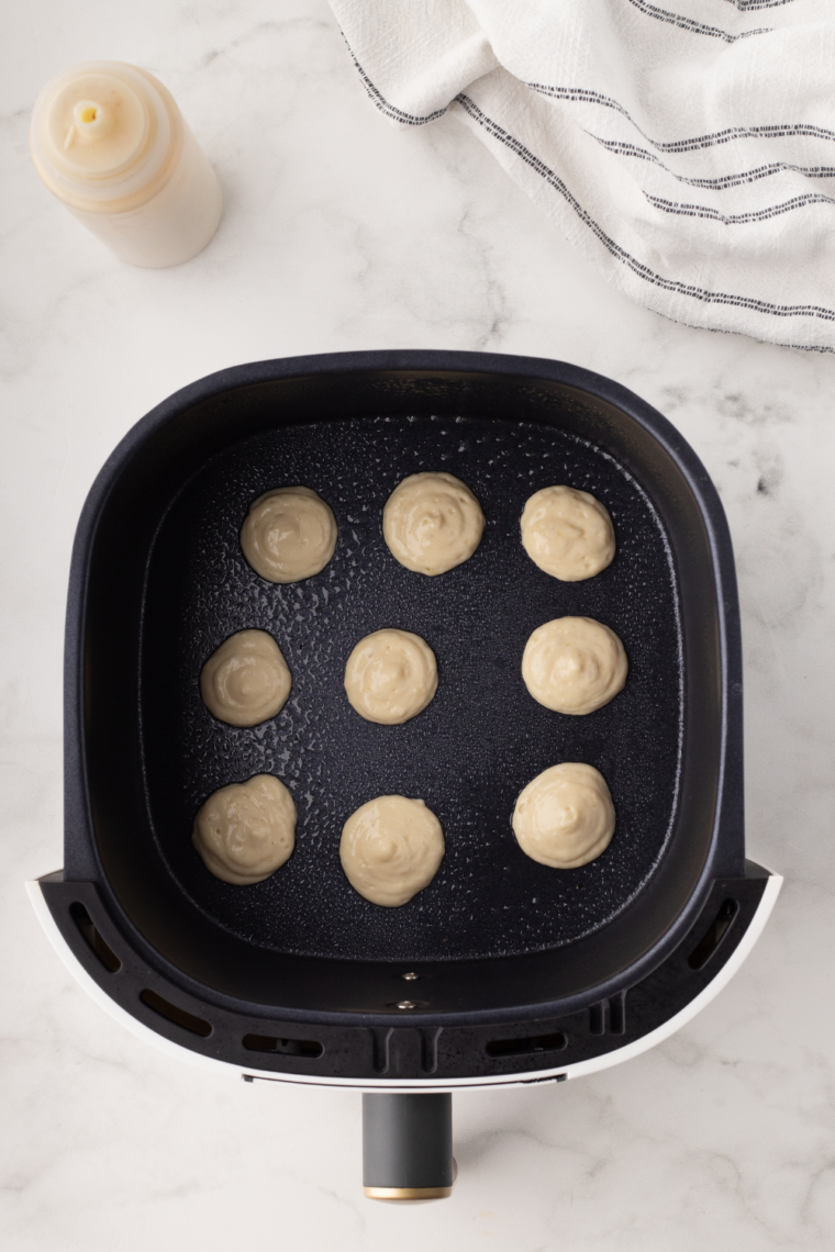 Transferring pancake batter into a squeeze bottle or piping bag to create small dots of batter in the air fryer basket.