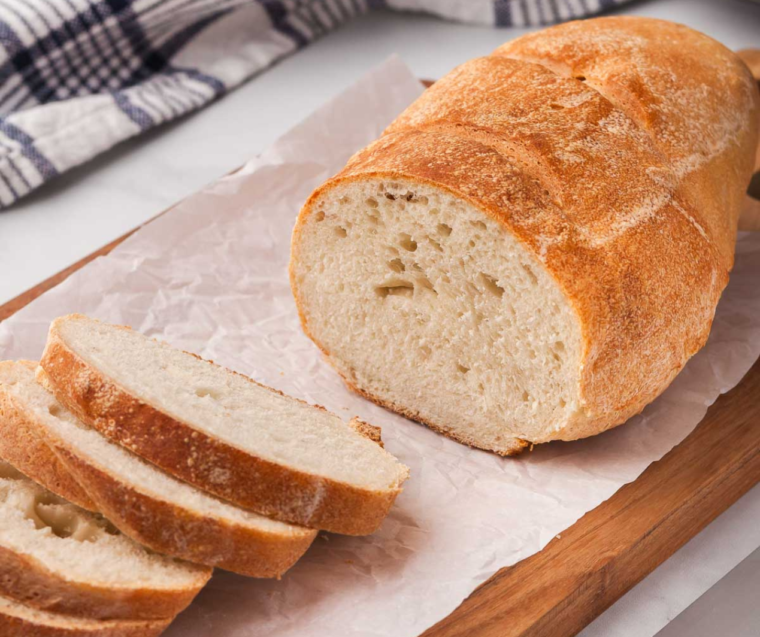 Golden crusty air fryer sourdough bread loaf sliced on a wooden cutting board
