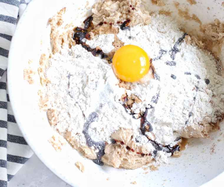 Adding flour baking soda cinnamon ginger nutmeg and salt to cookie dough while mixing.