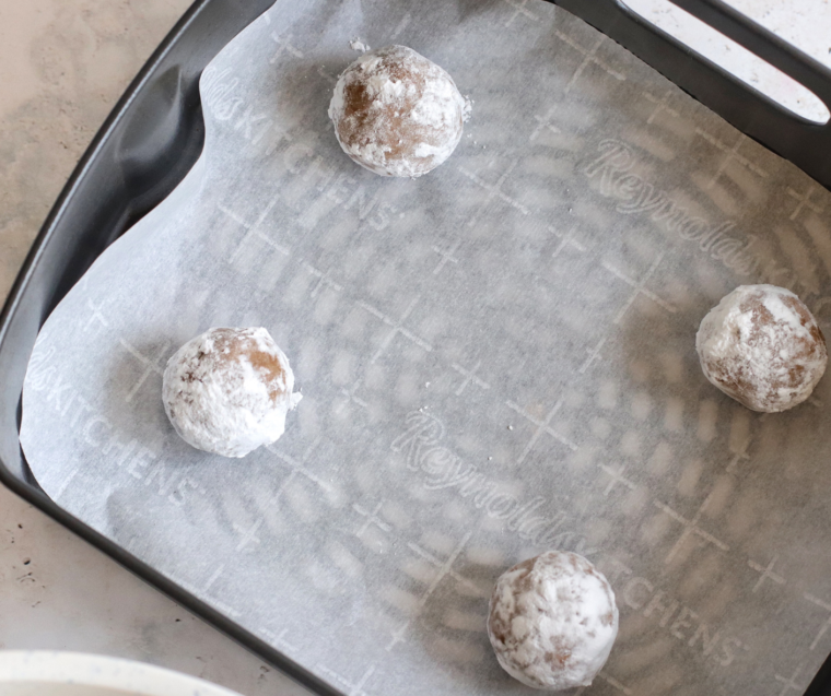 Gingerbread crinkle cookies spaced on parchment paper in air fryer, puffed and slightly crisp on the outside.