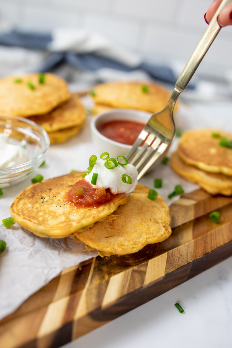 Plate of street corn fritters served with elote dipping sauce and lime wedges