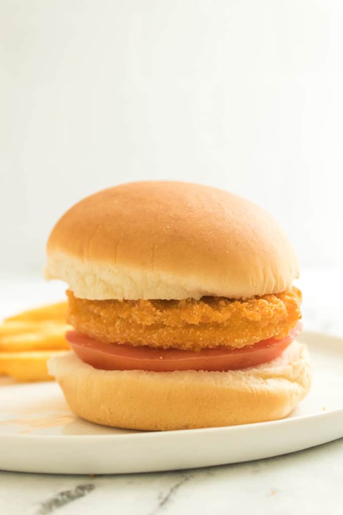side view: frozen chicken patty made in air fryer on a bun with a slice of tomato