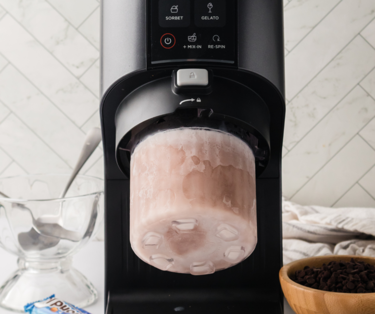 Frozen pumpkin ice cream pint installed in the Ninja Creami outer bowl