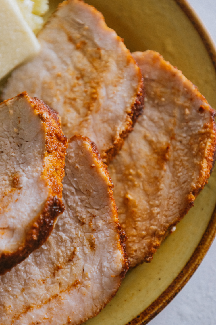 Sliced Ninja Foodi Grill pork tenderloin on a plate, juicy and char-grilled