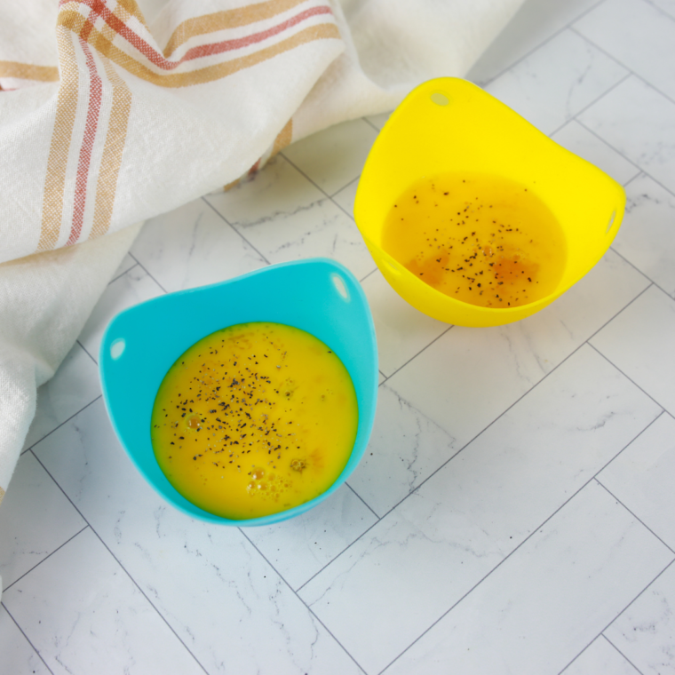 Eggs being cracked into a silicone mold for cooking in the air fryer.